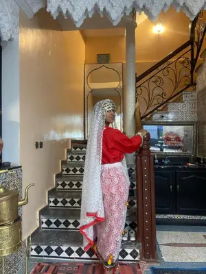 a woman standing on a staircase with a veil at Riad Dar Fadma in Ouarzazate