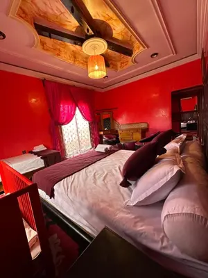 a bedroom with red walls and a large bed with pillows at Riad Dar Fadma in Ouarzazate