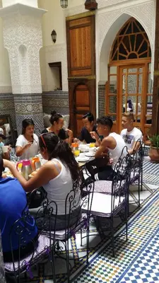 a group of people sitting at tables in a restaurant at Riad Taryana in Fès