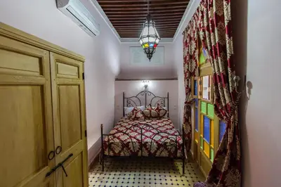 a small bedroom with a bed and a chandelier at Riad Taryana in Fès