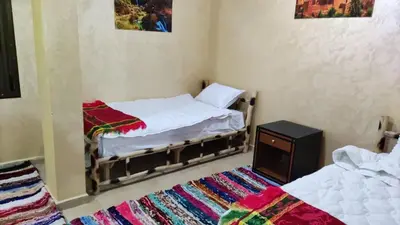 a small bedroom with two beds and a rug at auberge gite de jeunesse les Cascades in Setti Fatma
