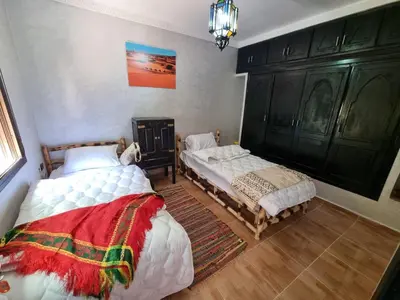 a bedroom with two beds and a chandelier at auberge gite de jeunesse les Cascades in Setti Fatma