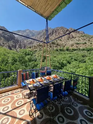a table and chairs on a balcony with a view of a mountain at auberge gite de jeunesse les Cascades in Setti Fatma