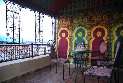 a balcony with a table and chairs and windows at Dar Hafsa in Fès