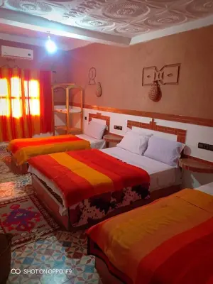 a room with three beds with colorful blankets at Hôtel Restaurant La Gazelle De Dades in Akhendachou nʼAït Ouffi