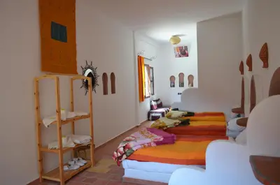 a room with two beds and a shelf in it at Hôtel Restaurant La Gazelle De Dades in Akhendachou nʼAït Ouffi