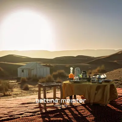 a table in the middle of a desert with the sun setting at Tinfou desert camp in Beni Ali