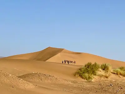 a group of people standing on top of a sand dune at Tinfou desert camp in Beni Ali