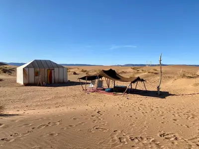 a tent in the desert with footprints in the sand at Tinfou desert camp in Beni Ali