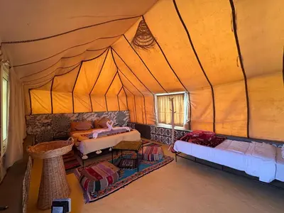 a room with a tent with a bed and a couch at Tinfou desert camp in Beni Ali