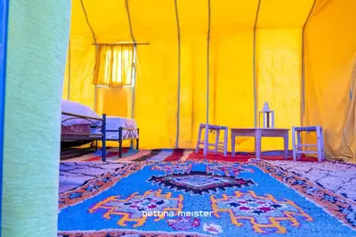a tent with a table and chairs and a rug at Tinfou desert camp in Beni Ali