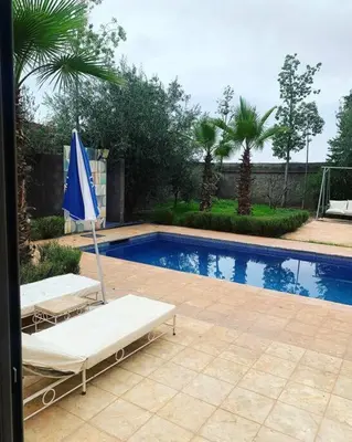 a swimming pool with two lounge chairs and an umbrella at Maison moalem in Marrakech