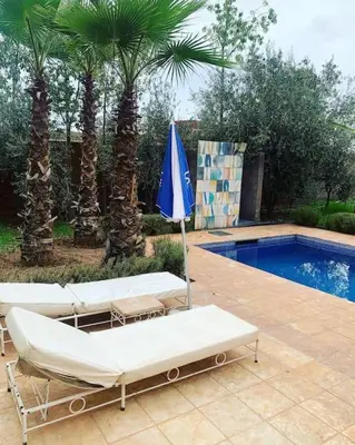 two lounge chairs and an umbrella next to a pool at Maison moalem in Marrakech