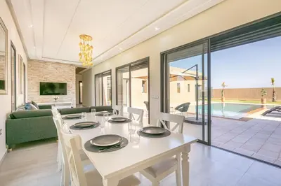 a dining room with a white table and chairs at Villa Sanna, élégante avec piscine Chauffée, jeux in Marrakech