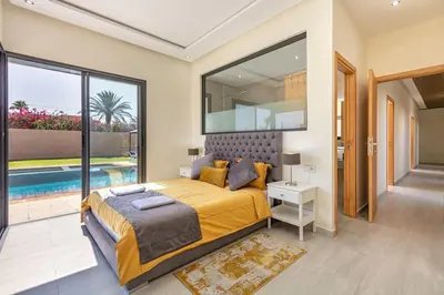 a bedroom with a large bed and a swimming pool at Villa Sanna, élégante avec piscine Chauffée, jeux in Marrakech