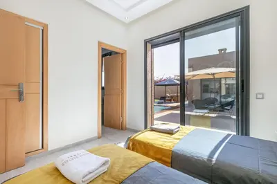 a bedroom with two beds and a large window at Villa Sanna, élégante avec piscine Chauffée, jeux in Marrakech
