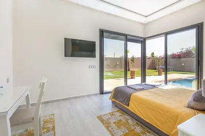 a bedroom with a bed and a sliding glass door at Villa Sanna, élégante avec piscine Chauffée, jeux in Marrakech