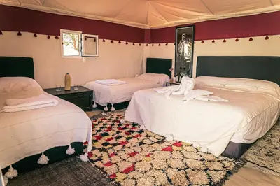 a bedroom with two beds and a rug at Merzouga Prestige Camp in Merzouga