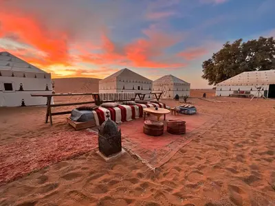 a group of buildings in the middle of the desert at Merzouga Prestige Camp in Merzouga