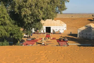 a group of buildings in the middle of a desert at Merzouga Prestige Camp in Merzouga