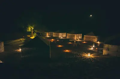 a night time view of a compound with lights at Merzouga Prestige Camp in Merzouga