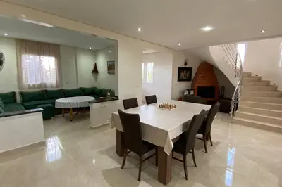 a dining room and living room with a table and chairs at Maison unique avec une magnifique piscine in El Kelaa des Srarhna