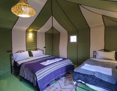 two beds in a room with green and white at Merzouga Magic Carpet camp in Merzouga