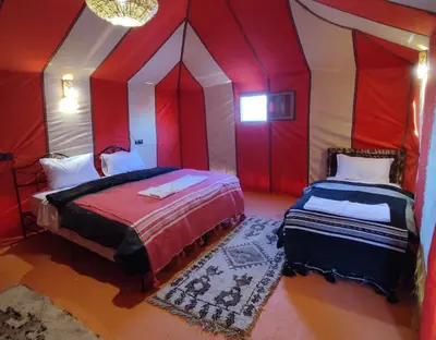 a bedroom with two beds with red and white walls at Merzouga Magic Carpet camp in Merzouga