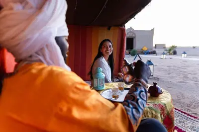 a woman sitting at a table in a tent at Camp Familia Erg Chebbi in Merzouga