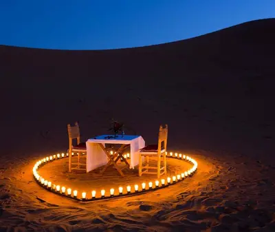 a table and chairs in the desert with lights at Merzouga luxury magic nights in Merzouga