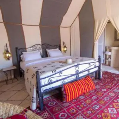 a bedroom with a large bed with a red rug at Merzouga luxury magic nights in Merzouga