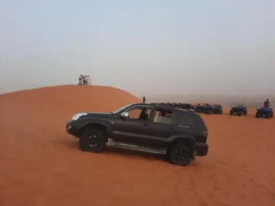 a black truck in the desert with a group of motorcycles at Merzouga Majestic Camp in Merzouga