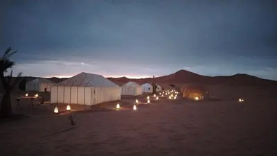 a group of tents in the desert at night at Merzouga Majestic Camp in Merzouga