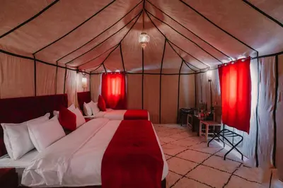 a bedroom with a bed in a tent with red curtains at Merzouga Majestic Camp in Merzouga