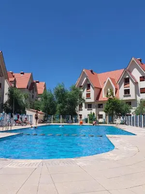 a large blue swimming pool in a courtyard with houses at Ifrane apartment with swimming pool in Ifrane