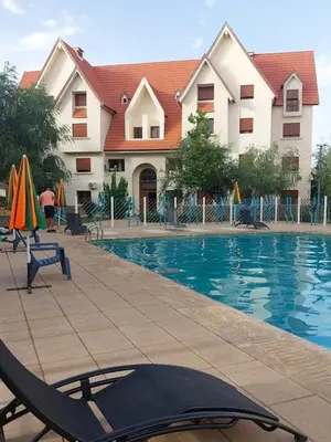 a swimming pool with chairs and umbrellas in front of a building at Ifrane apartment with swimming pool in Ifrane