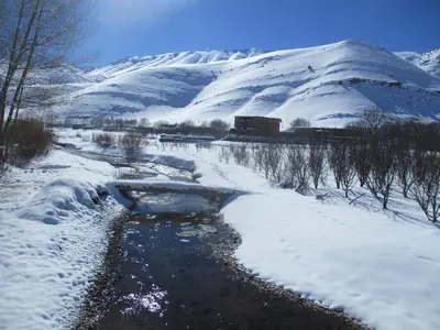 a stream in the snow with a mountain in the background at Safranière du M' Goun in Aguerd nʼOuzrou