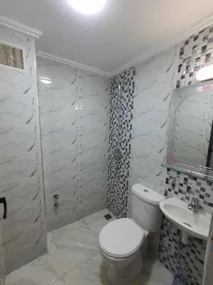 a white bathroom with a toilet and a sink at Appartement Dar Meknès in Meknès