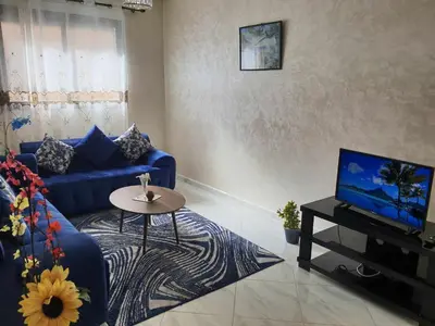a living room with a blue couch and a tv at Appartement Dar Meknès in Meknès