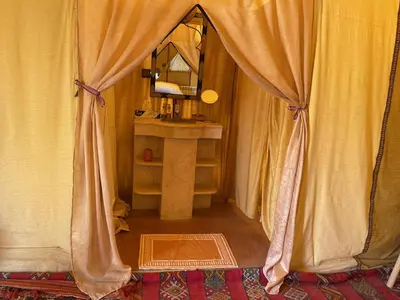 a room with a curtain and a sink and a mirror at Arena Desert Camp & Activitys in Merzouga