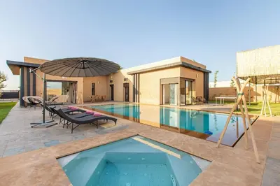 a swimming pool with an umbrella next to a house at villa Safa, confort et relax, piscine Chauffée, hammam in Marrakech
