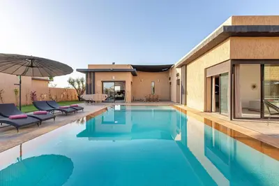 a pool with chairs and an umbrella next to a house at villa Safa, confort et relax, piscine Chauffée, hammam in Marrakech