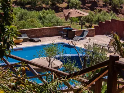 a swimming pool with a patio and an umbrella at Hotel Bin El Ouidane in Bine el Ouidane