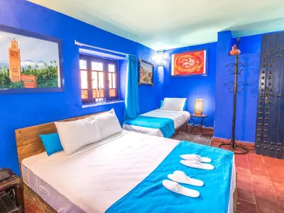a bedroom with blue walls and a bed with two towels on it at Hotel Bin El Ouidane in Bine el Ouidane