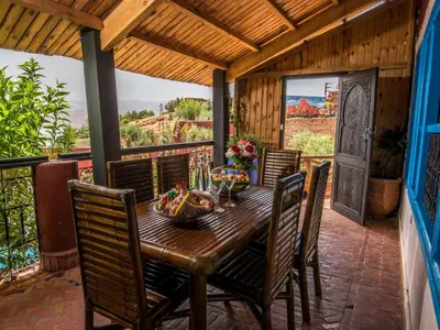 a wooden table and chairs on a patio with a view at Hotel Bin El Ouidane in Bine el Ouidane