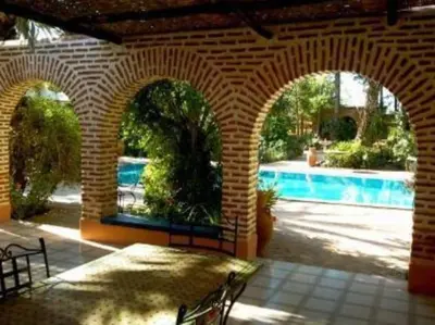 a brick patio with a table and a swimming pool at Villa Yasmina in Douar Blidene