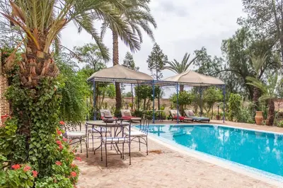 a pool with a table and chairs next to a palm tree at Villa Yasmina in Douar Blidene