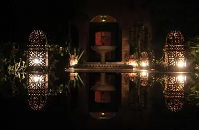 a reflection of a fountain in a pool at night at Villa Yasmina in Douar Blidene