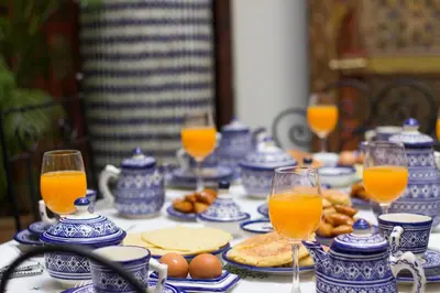 a table with blue and white china and glasses of orange juice at Riad Sanaa Rose in Fès