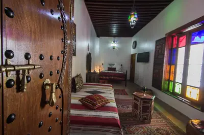 a bedroom with a wooden door with a bed in it at Riad Sanaa Rose in Fès